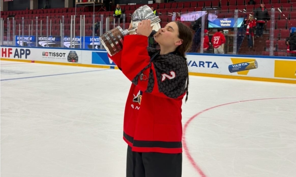 A female hockey player holds up the championship cup.
