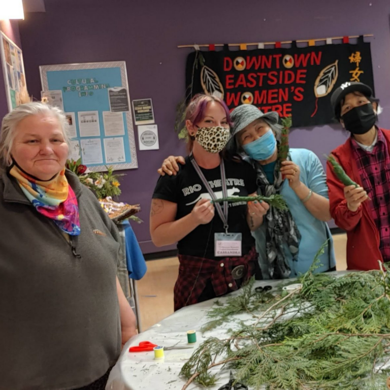 Cassandra and three others look directly at the camera wearing face masks. One person has their arm around Cassandra's shoulder.