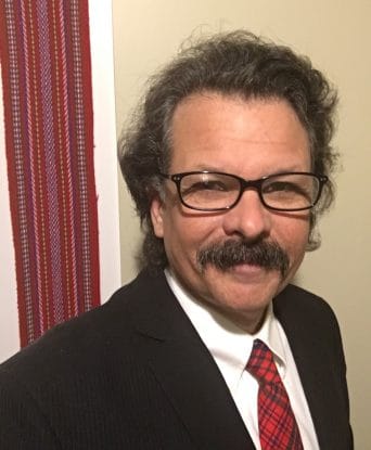 Lennox Fraser smiles slightly toward the camera, wearing a suit.