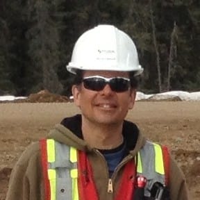 Lennox Fraser looks directly at the camera, wearing a hard hat, sunglasses, and a high visibility vest.