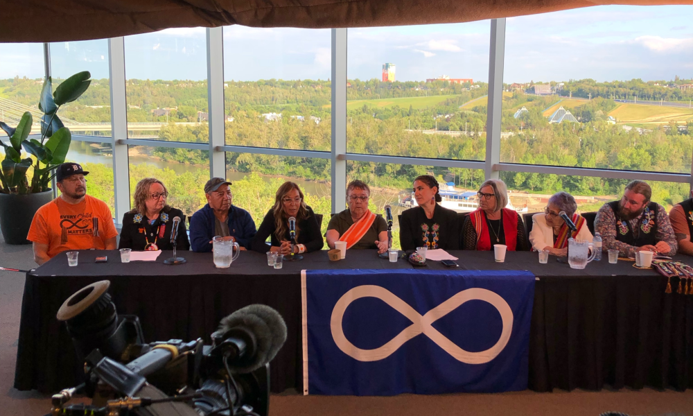 People sitting behind table holding a press conference