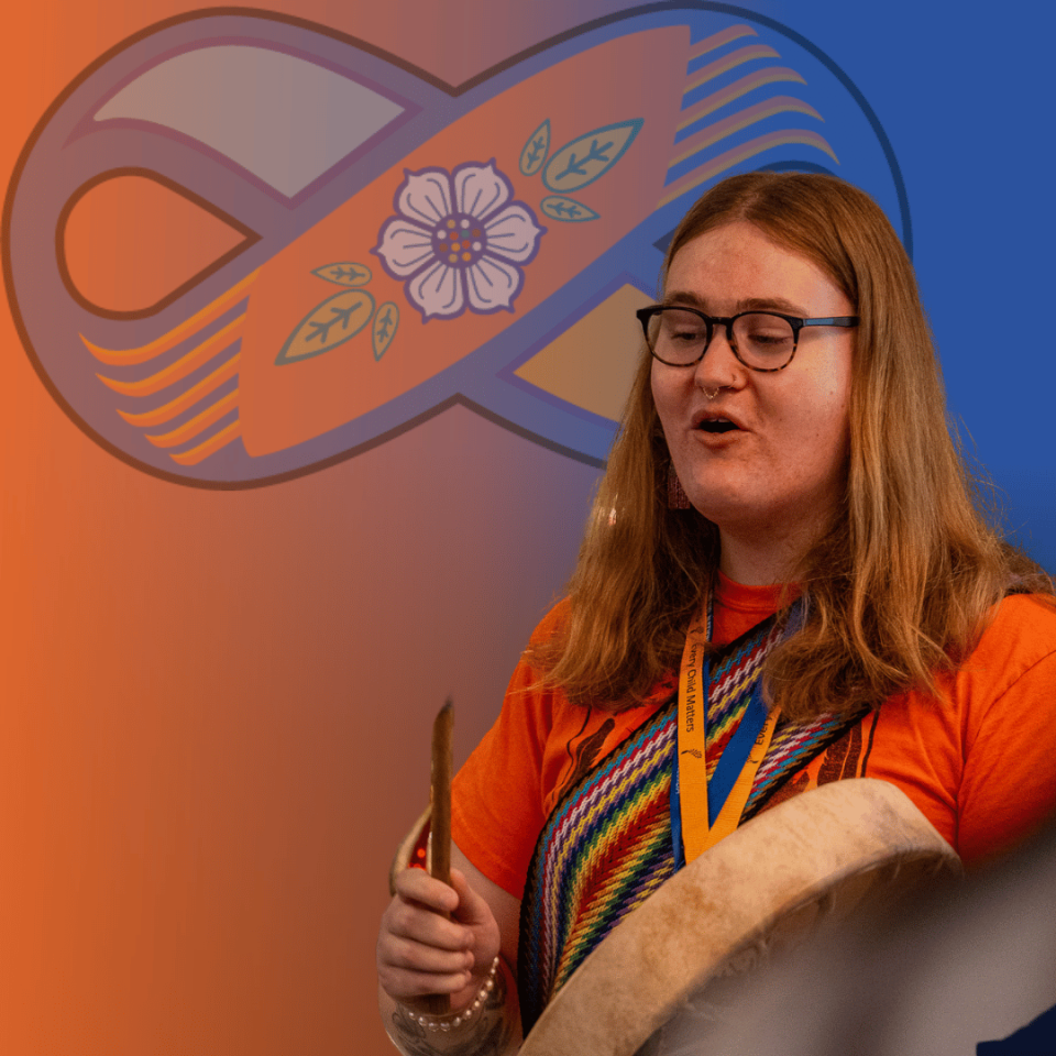Image of a young person drumming with the youth orange and blue Metis sash logo in the background.