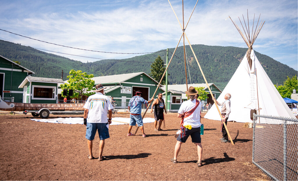 A group of men is assembling a large white Tipi.