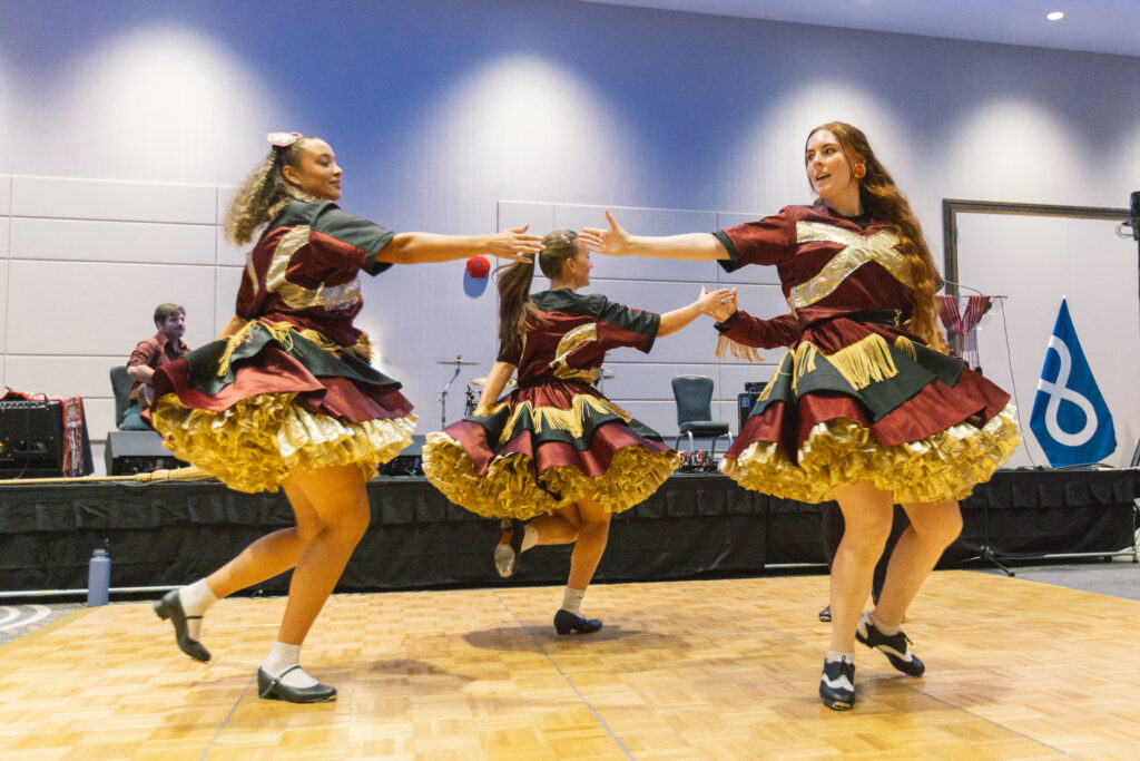 A group of women jigging on a dance floor at a cultural event.