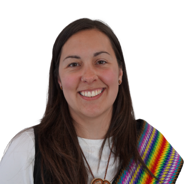 Sarah Curr is smiling in a white shirt with a rainbow Métis sash draped over their shoulder against a white background.